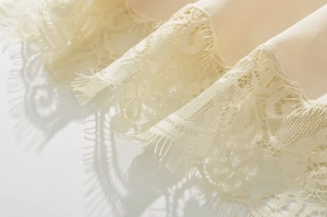 Intricate eyelash lace detail on cream silk dress with elegant mirror reflections