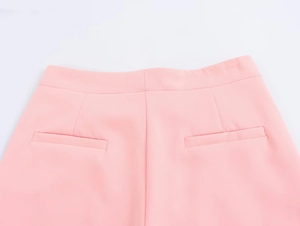 Dettaglio dei pantaloni rosa a vita alta con tasche a filetto e cuciture di precisione