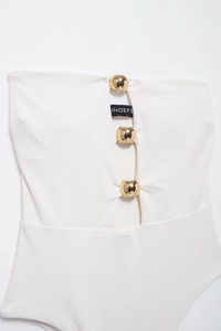 Dettaglio del costume intero bianco a fascia con sfere dorate ed etichetta INDEFE