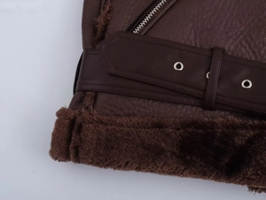 Détail de la veste aviateur marron foncé montrant la texture cuir et la boucle de ceinture
