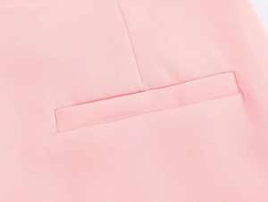 Dettaglio ravvicinato di una tasca a filetto rosa su pantaloni con fine trama di tessuto