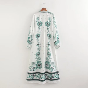 Bohemian floral maxi dress with V-neck and green plant print on white fabric background