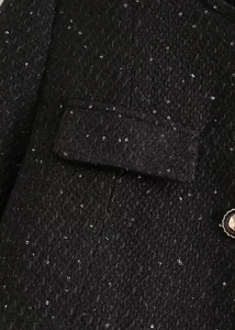 Détail du tissu en tweed noir avec paillettes argentées et bouton décoratif en métal