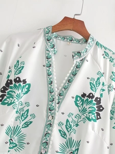 Detailed close-up of V-neck with lace trim and shell buttons on floral white blouse