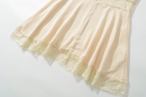 Detail view of champagne satin dress hem featuring delicate eyelash lace stitching
