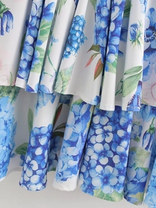 Close-up of ruffled hem with vibrant blue hydrangea floral print on lightweight white fabric