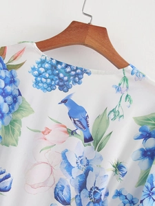 Detail of floral bird print on V-neck white summer dress with blue hydrangeas