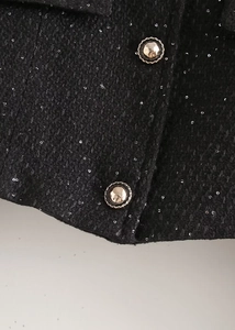 Détail du tissu tweed noir avec paillettes argentées et boutons métalliques vintage