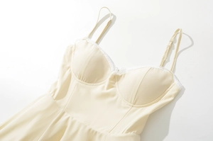 Detail of cream yellow lace dress featuring adjustable straps and silk texture fabric