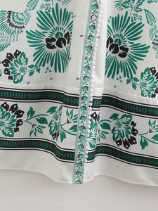 Close-up of bohemian floral print dress with pearly buttons and pom-pom trim detail