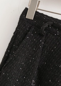 Gros plan sur le tissu en tweed noir à paillettes argentées avec une poche latérale
