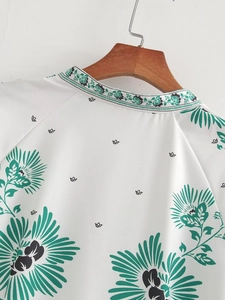 Detail showing high-quality polyester fabric with green and black floral print and stand collar