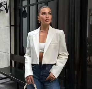 Detailed view of women's white cropped blazer with notch lapels in urban street style