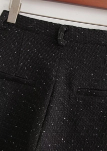 Détail rapproché du short en tweed noir avec paillettes scintillantes et poche cousue