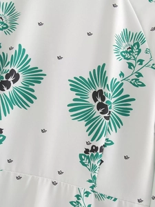 Detail of vibrant green and black floral print on white summer dress chiffon fabric