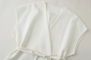Dettaglio del gilet bianco senza maniche in misto lino con scollo a V e laccio in vita