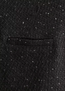 Détail du tissu en tweed noir avec paillettes argentées et couture de la poche