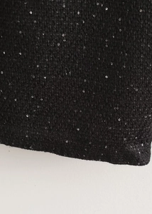 Détail de tissu en tweed noir avec paillettes argentées et texture tissée