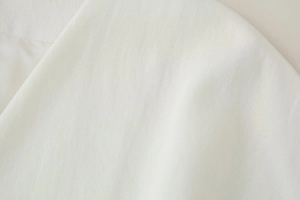 Dettaglio del tessuto misto lino bianco che mostra la trama a saia del gilet e dei pantaloni
