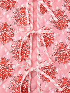 Detalle de chaleco acolchado rosa con estampado floral, costuras de rombos y cierre de lazo