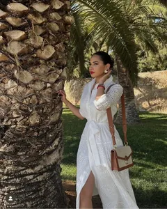 Detail of white cotton midi dress featuring intricate Broderie Anglaise and waist tie belt