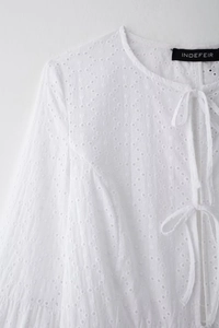 Détails de la broderie anglaise délicate et du col à lacets sur cette chemise blanche