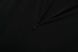 Détail d'une fermeture éclair invisible de qualité sur une robe en maille noire ajustée