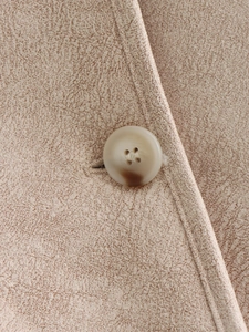 Detail of marble-patterned button and textured woven fabric on casual women's jacket