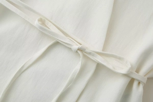 Dettaglio del tessuto bianco in misto lino con cintura annodata e trama in diagonale