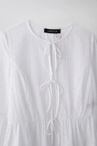 Détail du haut en coton blanc avec broderie anglaise, lacets sur le devant et col rond