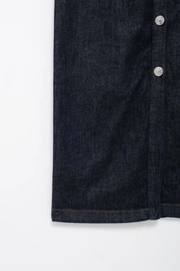 Détail d'une robe en jean indigo foncé avec boutons métalliques et surpiqûres jaunes