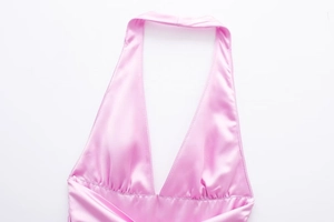 Dettaglio dell'abito halter in raso rosa con texture setosa e scollo a V profondo
