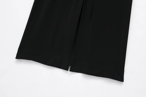 Détail de l'ourlet d'une robe en maille noire avec fente centrale et texture fine