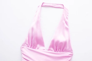 Dettaglio del top a lupetto in raso rosa con scollo a V e design a pieghe sul petto