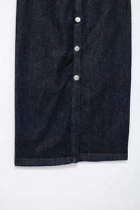 Détails d'une robe midi en jean bleu foncé avec boutons métalliques et coutures brunes