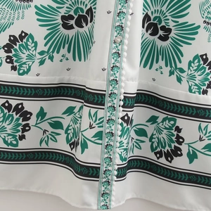 White V-neck maxi dress featuring green floral print with pompom lace and button details