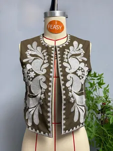 Gros plan sur la broderie florale blanche de la veste sans manches marron