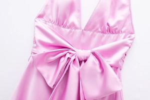Dettaglio di un grande fiocco di raso rosa sul retro di un abito setoso senza schienale