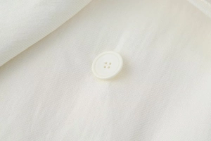 Dettaglio macro di un bottone bianco a quattro fori e del tessuto in misto lino