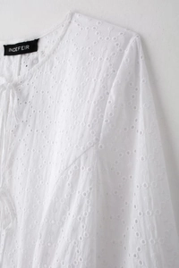 Gros plan détaillé sur la broderie anglaise blanche et le cordon de serrage au col