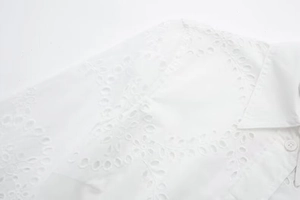 Detailed view of white eyelet lace embroidery and floral patterns on cotton shirt