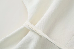 Dettaglio ravvicinato del tessuto in misto lino bianco con trama a saia e cuciture in vita