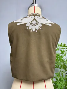 Détail de broderie florale blanche au dos d'un gilet sans manches marron