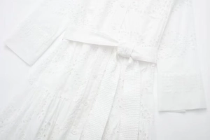 Close-up of white midi dress showing delicate floral embroidery and button detail