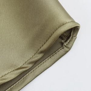 Detailed close-up of smooth olive satin fabric with high-quality edge stitching seams