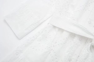 Detailed view of white eyelet embroidery midi dress with buttons and waist tie