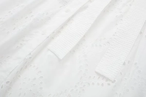 Detail of white midi dress showing delicate eyelet embroidery and floral cutouts