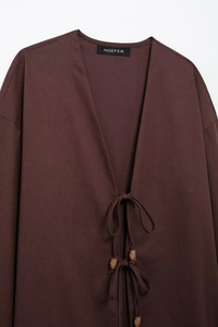 Détail d'un haut kimono en lin marron foncé avec col en V et fermeture à perles