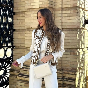 Détails de broderie sur gilet marron avec chemise en satin et pantalon blanc chic
