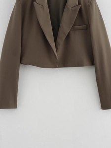 Detail of cropped blazer featuring notch lapels and a sleek chest pocket in brown fabric